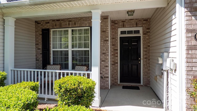 property entrance featuring brick siding and a porch