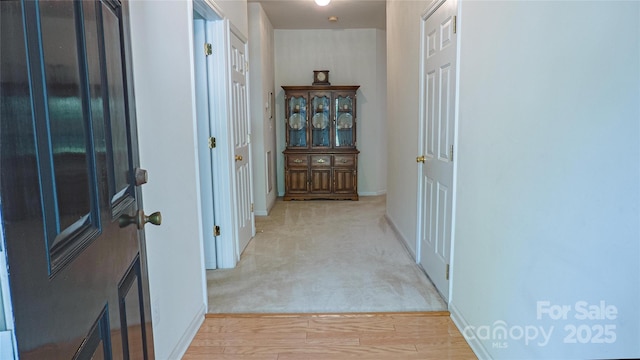 hallway with light colored carpet and baseboards