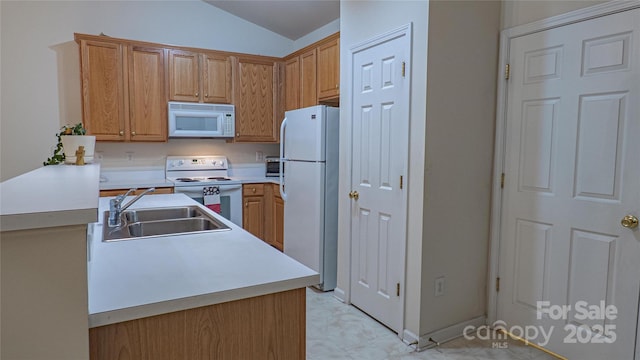 kitchen featuring white appliances, a peninsula, light countertops, lofted ceiling, and a sink