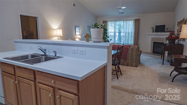kitchen featuring a fireplace, a ceiling fan, vaulted ceiling, a sink, and open floor plan