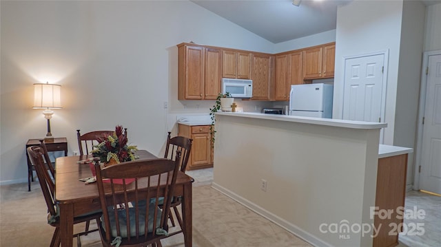 kitchen featuring light countertops, a center island, white appliances, and lofted ceiling