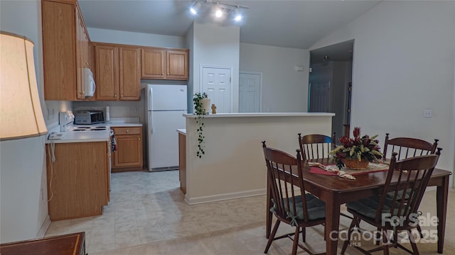 kitchen featuring a toaster, white appliances, light countertops, brown cabinets, and lofted ceiling
