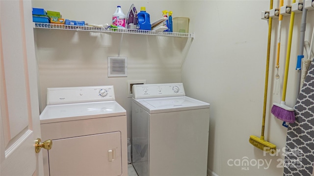 clothes washing area with washing machine and dryer, laundry area, and visible vents
