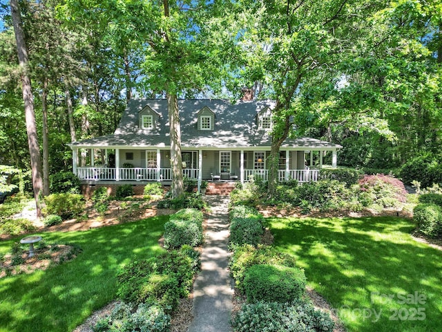 farmhouse-style home with a chimney, a porch, and a front lawn