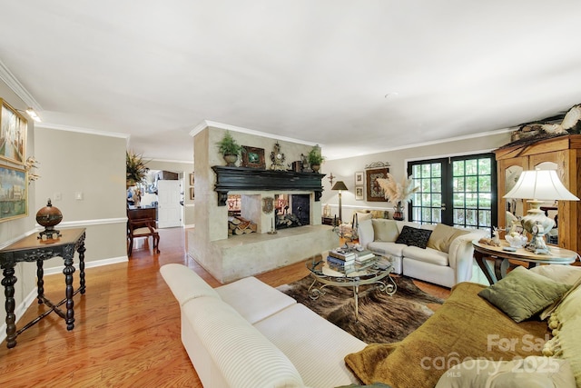 living room with crown molding, baseboards, light wood finished floors, and a high end fireplace