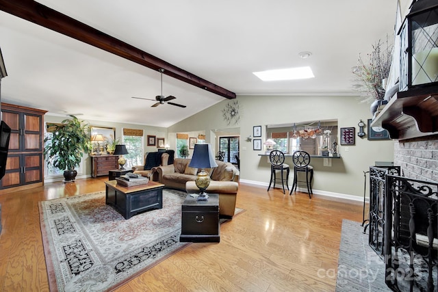 living area featuring baseboards, ceiling fan, wood finished floors, and vaulted ceiling with beams
