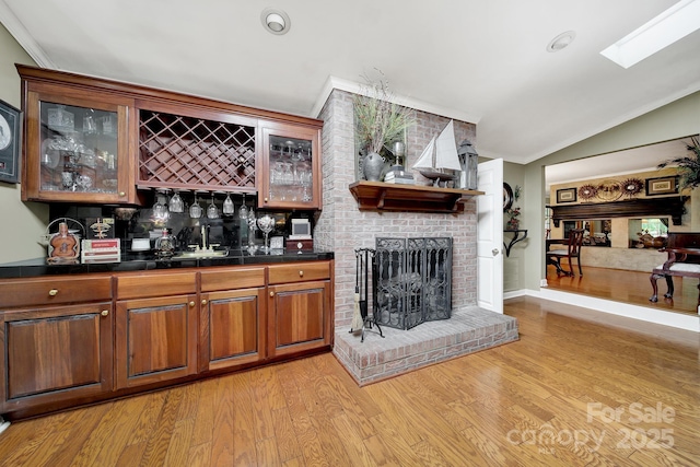 bar featuring bar, tasteful backsplash, a fireplace, lofted ceiling, and ornamental molding