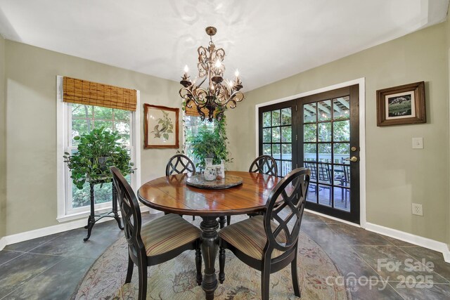 dining room with stone tile floors, baseboards, and a chandelier