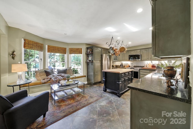 kitchen with open shelves, appliances with stainless steel finishes, a chandelier, a center island, and recessed lighting
