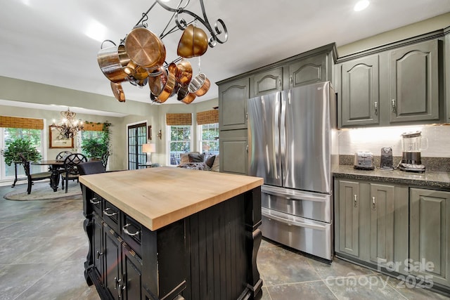 kitchen featuring an inviting chandelier, wooden counters, freestanding refrigerator, stone finish flooring, and a kitchen island