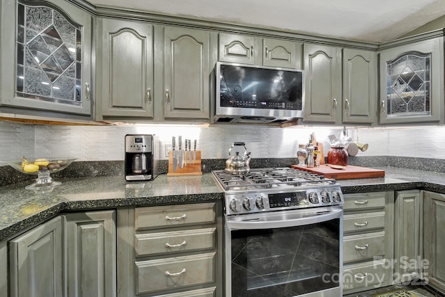kitchen featuring glass insert cabinets, tasteful backsplash, stainless steel appliances, and gray cabinetry