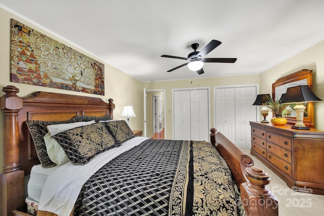 bedroom with crown molding, multiple closets, and a ceiling fan