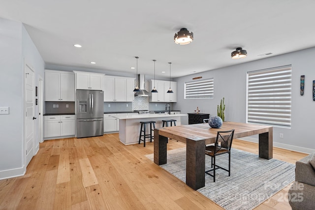 dining room featuring light wood-type flooring, baseboards, visible vents, and recessed lighting