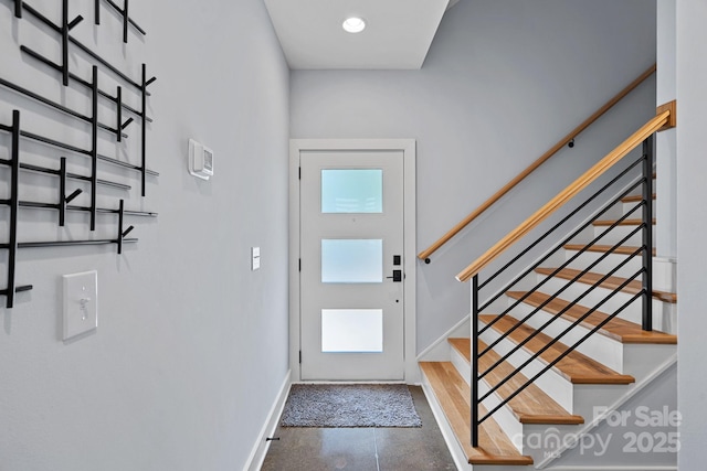 entrance foyer with concrete floors, stairway, and baseboards