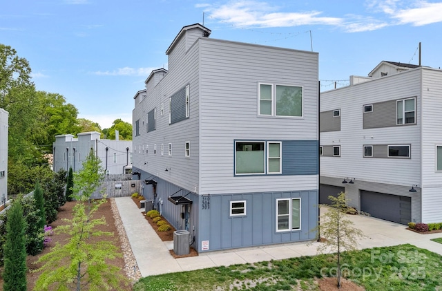 back of house with a garage and central AC