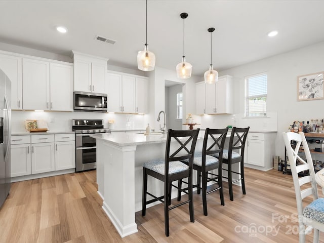 5532 Muckross Ln, Fort Mill, SC 29707 - kitchen with backsplash, light wood-style floors, visible vents, a center island with sink, and stainless steel appliances
