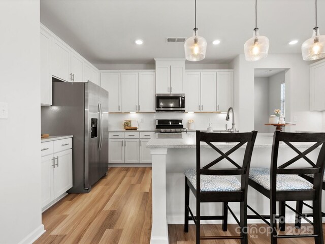 5532 Muckross Ln, Fort Mill, SC 29707 - kitchen featuring tasteful backsplash, light wood-type flooring, visible vents, a breakfast bar area, and stainless steel appliances