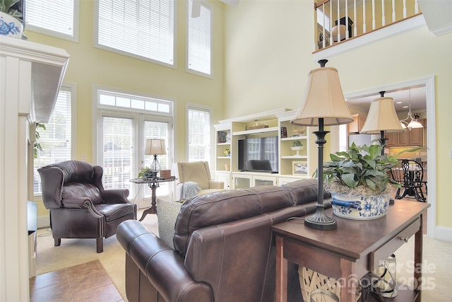 living area with a high ceiling and light colored carpet