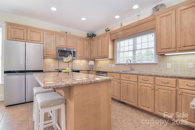 kitchen featuring stainless steel appliances, a breakfast bar, a sink, and crown molding