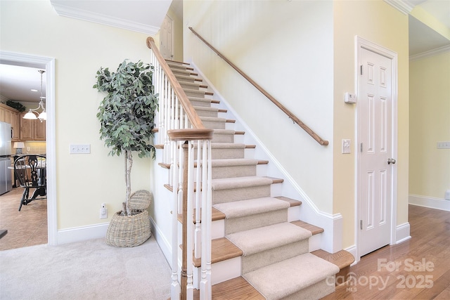 stairs with baseboards, ornamental molding, and carpet floors