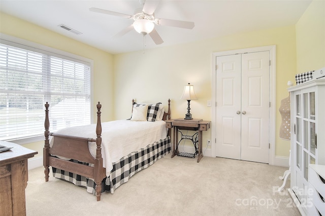 bedroom featuring a closet, baseboards, visible vents, ceiling fan, and light colored carpet