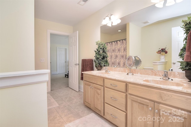 bathroom featuring toilet, double vanity, a sink, and visible vents