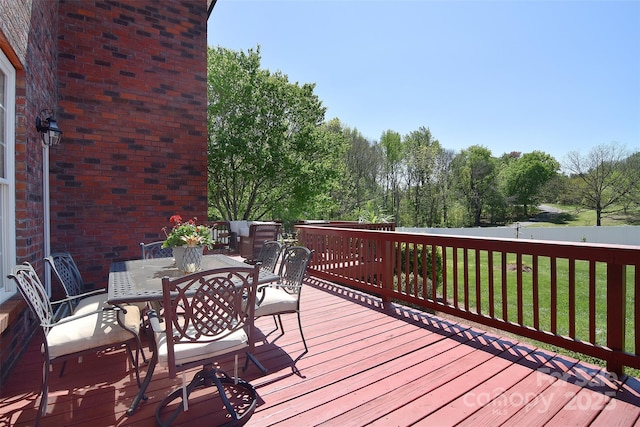 deck with outdoor dining area and a lawn