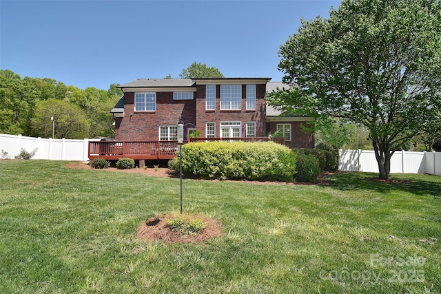 rear view of property with a yard, a wooden deck, a fenced backyard, and brick siding