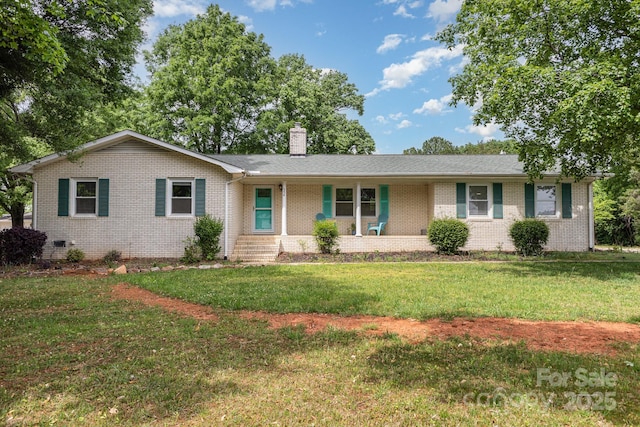 ranch-style home featuring a chimney, a front yard, a porch, and brick siding