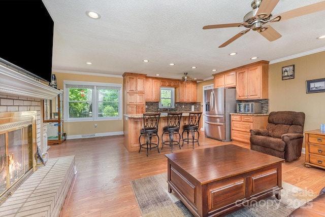 living area with crown molding, light wood finished floors, and ceiling fan