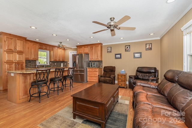 living room with light wood-style floors, ornamental molding, ceiling fan, and recessed lighting
