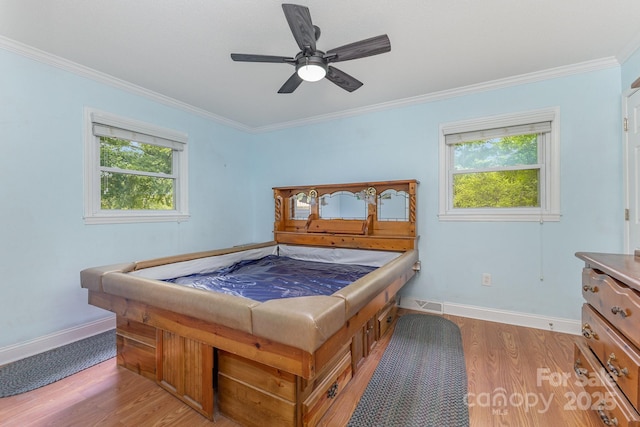 bedroom with crown molding, wood finished floors, and multiple windows