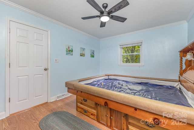 bedroom featuring baseboards, ornamental molding, ceiling fan, and light wood-type flooring