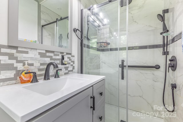 full bath with vanity, a marble finish shower, and backsplash