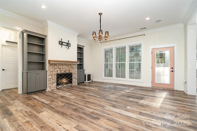 unfurnished living room featuring crown molding, a notable chandelier, visible vents, and wood finished floors