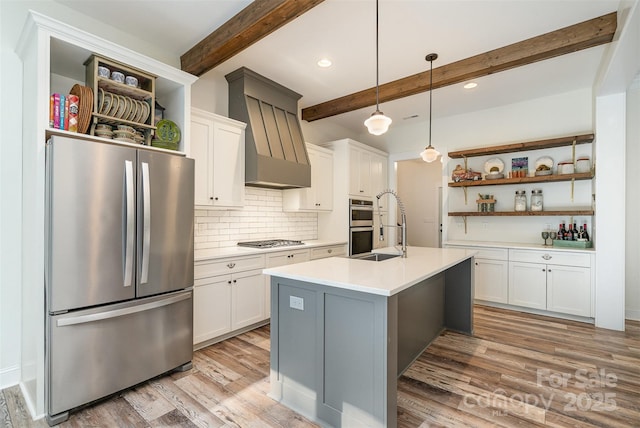 kitchen with a sink, open shelves, light wood-style flooring, beamed ceiling, and appliances with stainless steel finishes
