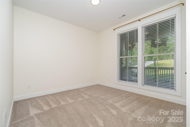 spare room featuring baseboards, visible vents, and carpet floors