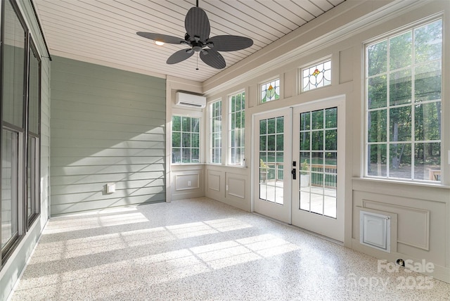 unfurnished sunroom featuring a ceiling fan, a wall unit AC, and french doors