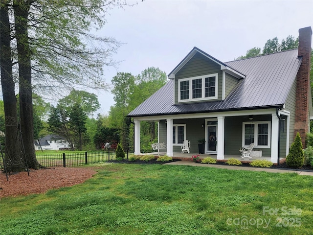 view of front of house with a chimney, a front lawn, a porch, metal roof, and fence