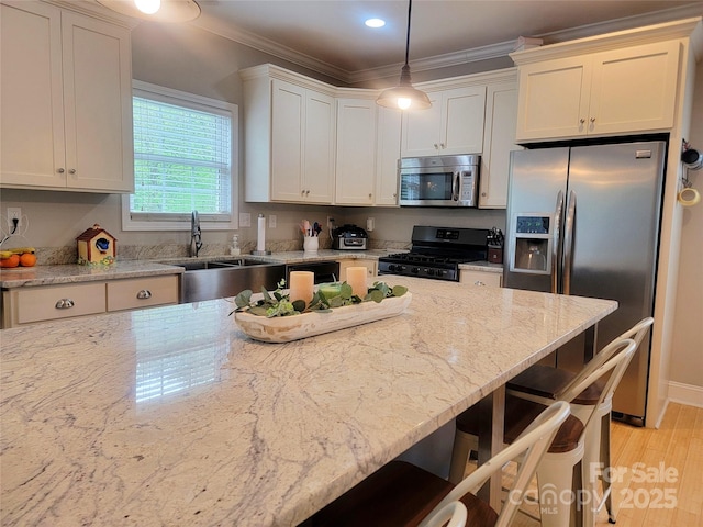 kitchen with hanging light fixtures, ornamental molding, appliances with stainless steel finishes, a breakfast bar, and light stone counters