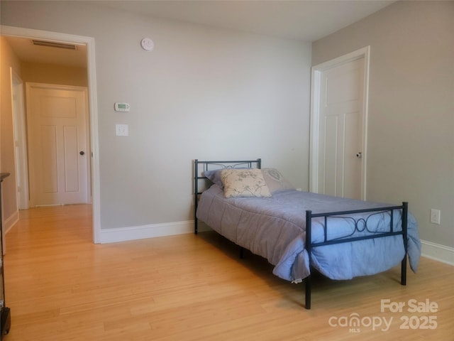 bedroom with light wood-style flooring, baseboards, and visible vents