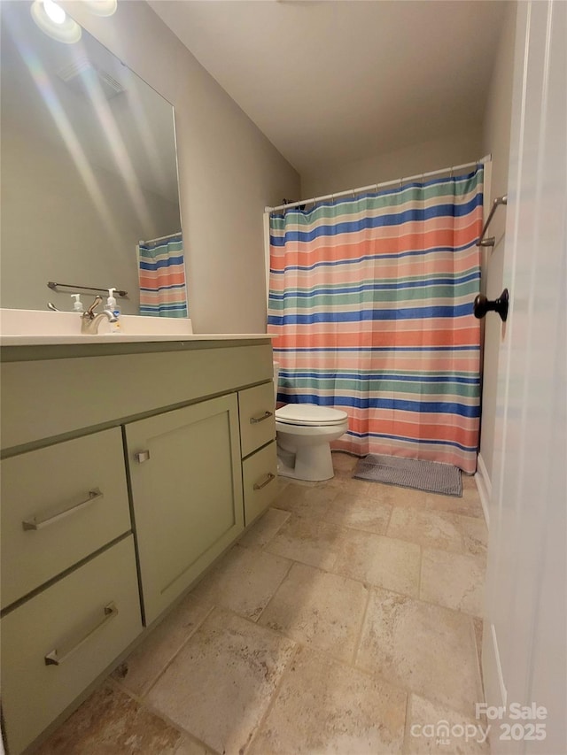 bathroom featuring stone tile flooring, toilet, vanity, and a shower with curtain