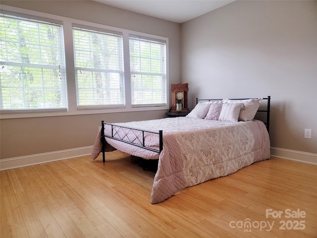bedroom with light wood-style flooring, baseboards, and multiple windows