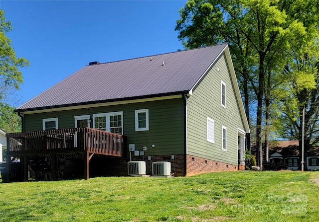 back of property with central AC unit, a deck, a lawn, and metal roof