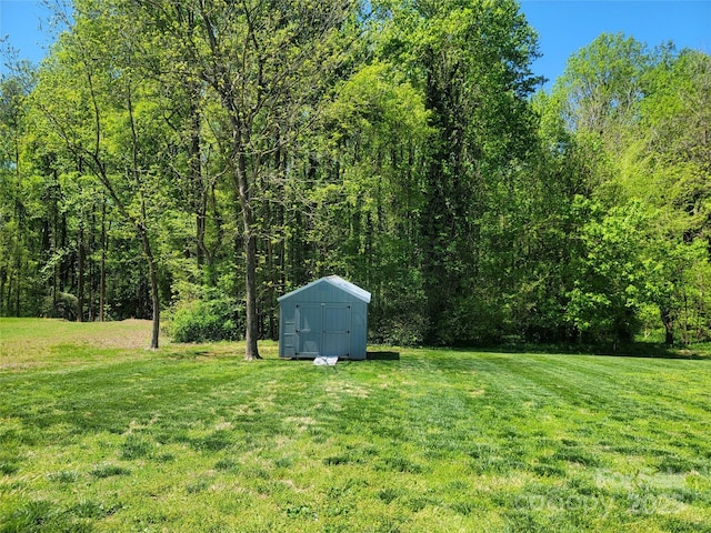 view of yard featuring a storage shed, a forest view, and an outbuilding
