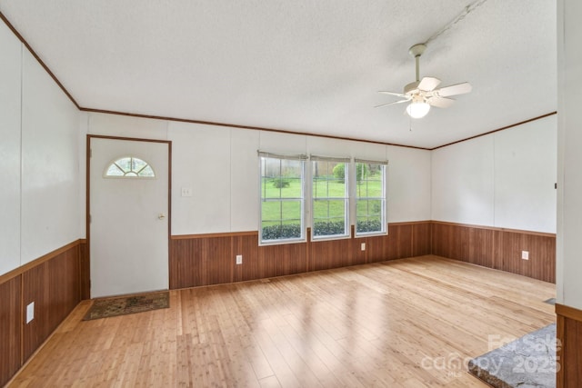 interior space featuring ornamental molding, ceiling fan, wood walls, a wainscoted wall, and hardwood / wood-style floors