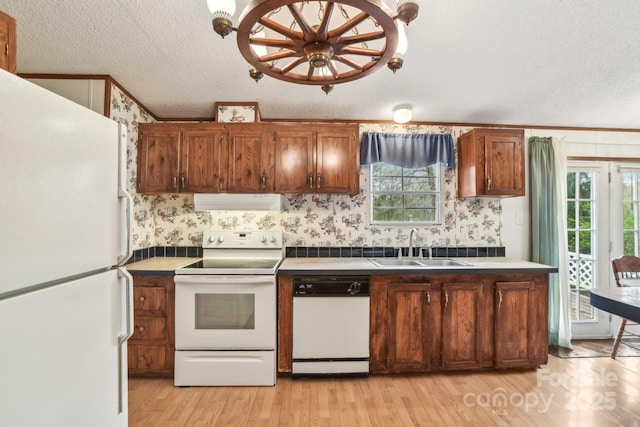 kitchen with white appliances, a textured ceiling, exhaust hood, light wood-style floors, and a sink