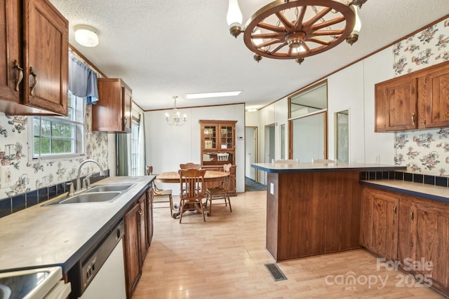 kitchen with visible vents, dishwasher, a sink, a chandelier, and wallpapered walls