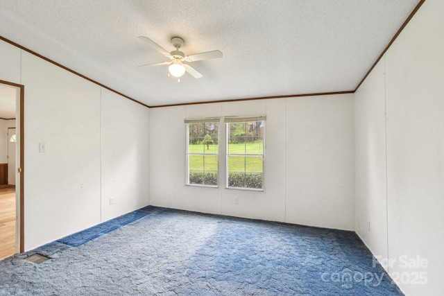 empty room featuring a textured ceiling, a ceiling fan, crown molding, and carpet floors
