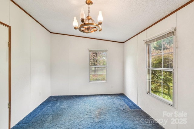 carpeted empty room featuring a textured ceiling, a notable chandelier, and ornamental molding